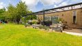Weitläufiger Garten mit gepflegtem Rasen, Spielbereich und hochwertiger Terrassenüberdachung.