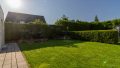 Pflegeleichter Garten mit blickdichtem Heckenzaun und liebevoll angelegten Beeten – perfekte Privatsphäre für erholsame Stunden im Grünen.